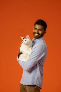 man in blue shirt holding a cat