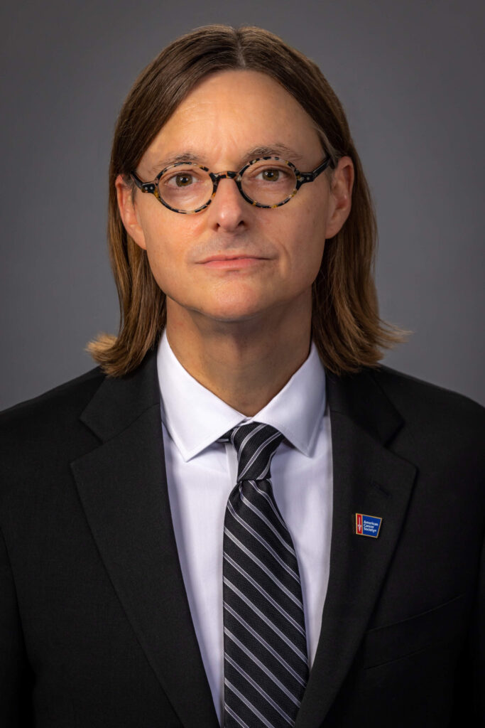 man in suit with long hair and tortoise shell glasses