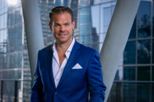 man in royal blue suit with white unbuttoned shirt and pocket square
