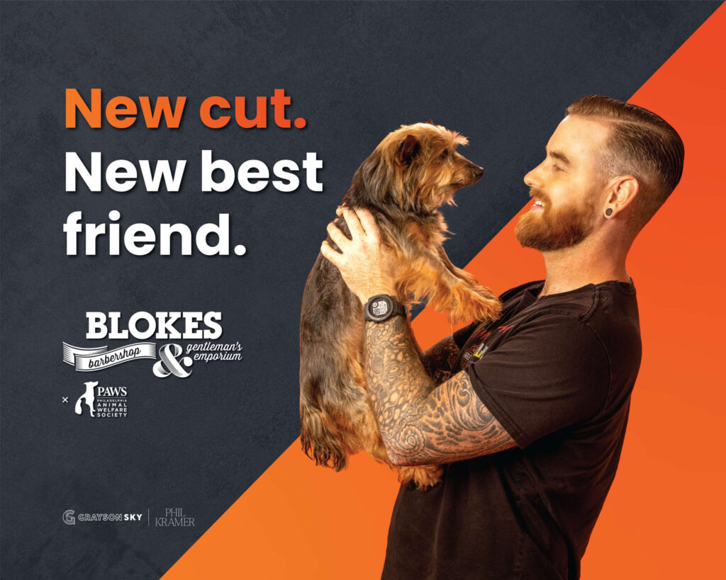 man with tattoos holding dog and smiling
