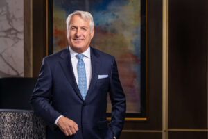 cheerful man in navy blue suit with arm resting on chair in condo lobby