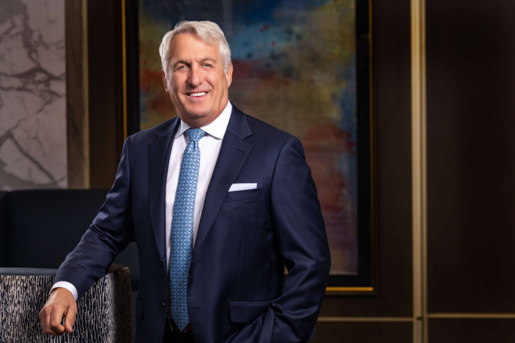 man smiling in classic navy blue suit against colorful abstract painting