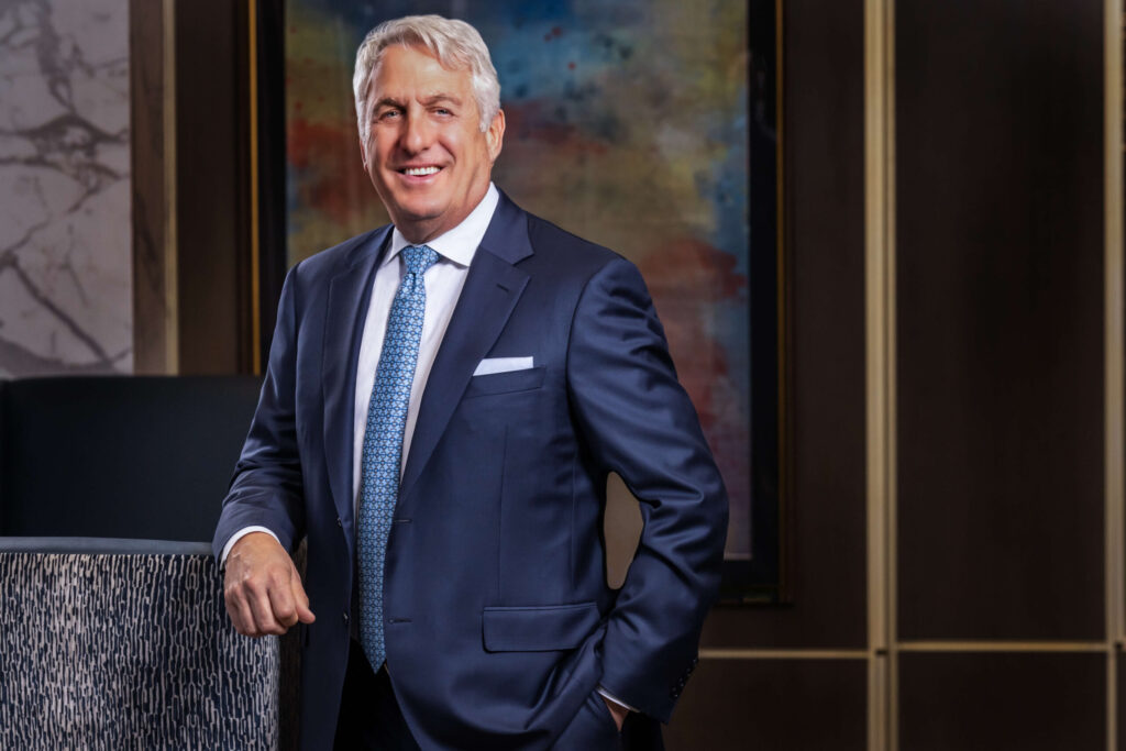 man smiling in classic navy blue suit against abstract painting