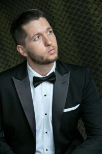groom in black tie tuxedo glancing off camera against funky modern wallpaper