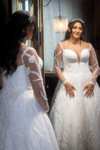 bride in white wedding dress looking mirror with joyful expression