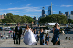 bride, groom, and wedding party walk up the rocky steps at the art museum in philly