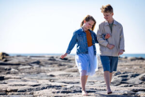 young boy and girl walking together on the rocks at the atlantic city beach
