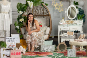 woman in white flower dress in brown wicker chair sitting around bridal accessories at shower