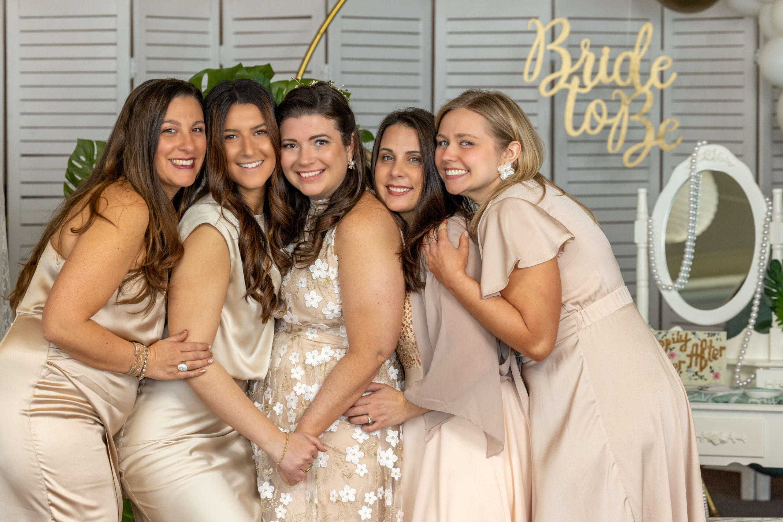 bridesmaids in champagne color dresses posing for photos at a tropical bridal shower
