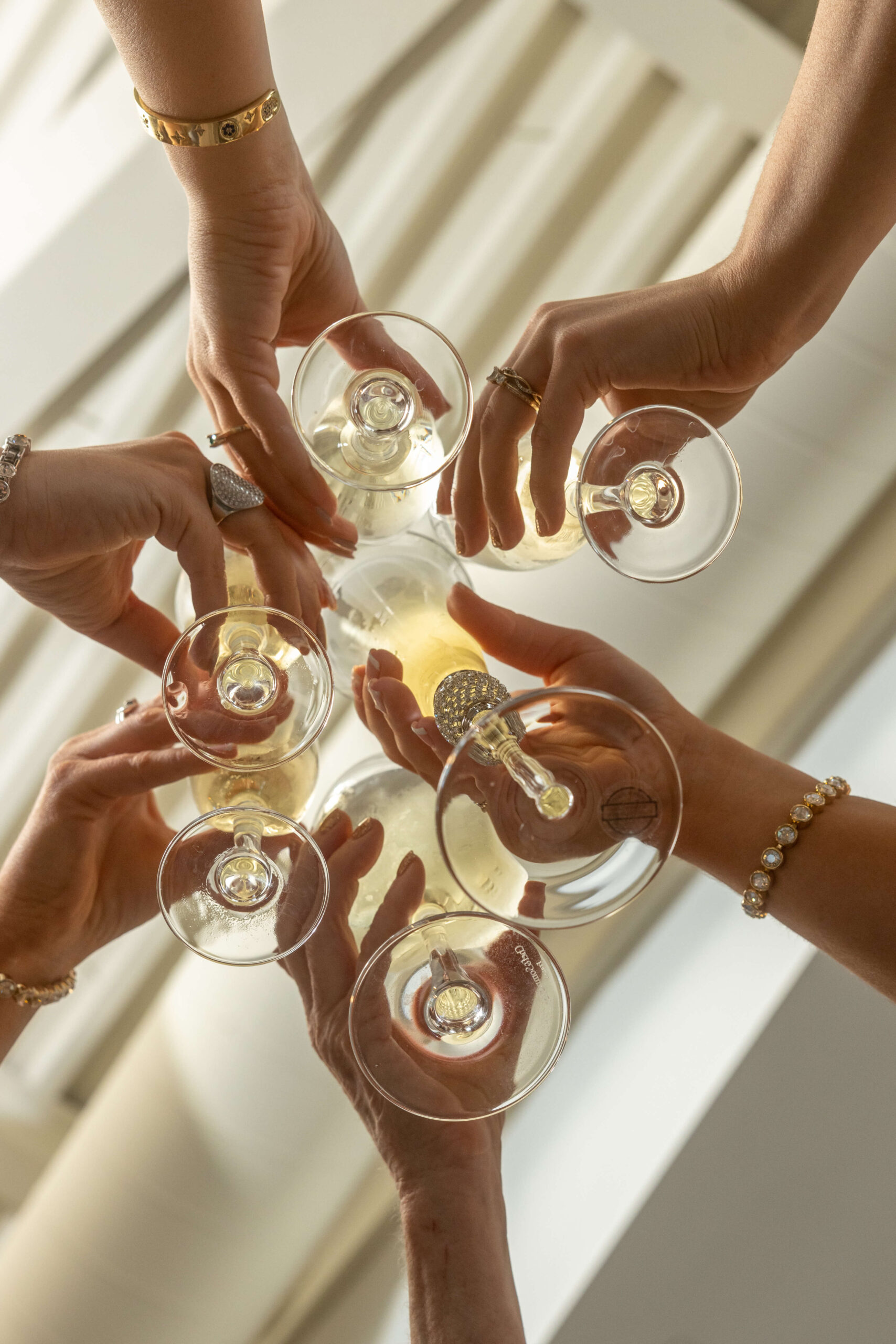 women's hands clanking and toasting champagne glasses from below