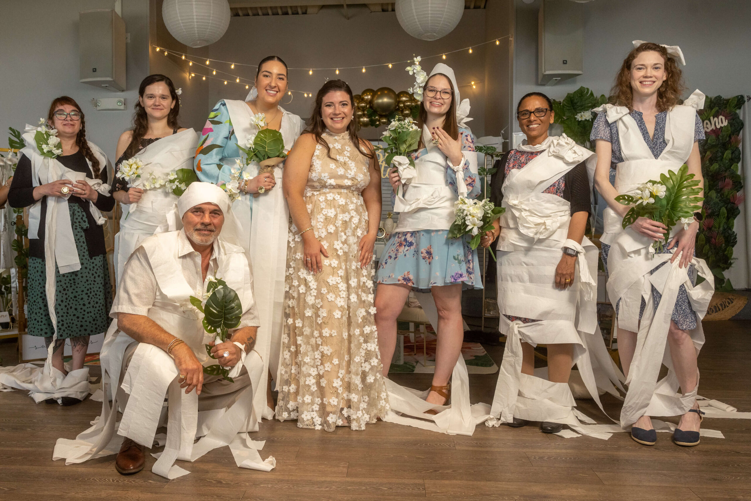 group photo of guests playing the toilet paper bridal shower game at tropical theme party