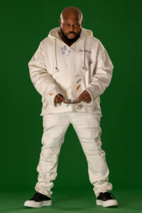 man with serious expression in white hoodie removing sunglasses