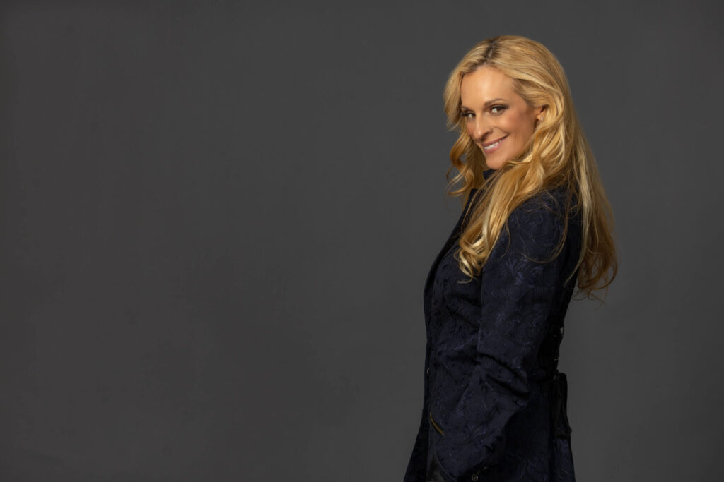 blonde woman smiling from side pose against grey background