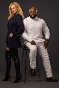 blonde woman and man in white turtleneck in a studio against a grey background