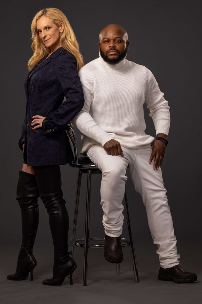 blonde woman and man in white turtleneck in a studio against a grey background
