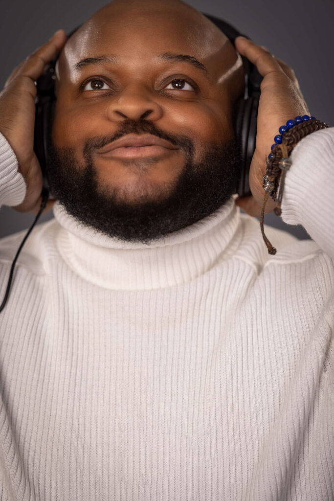 man wearing white turtleneck and listening to headphones with joyful expression on face