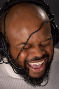 man screaming and laughing with headphone wires wrapped around his head