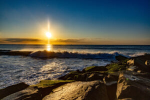 sunrise on Atlantic City beach in New Jersey with waves crashing against mossy rocks