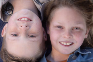 blonde boy and girl smiling into camera as they lay down