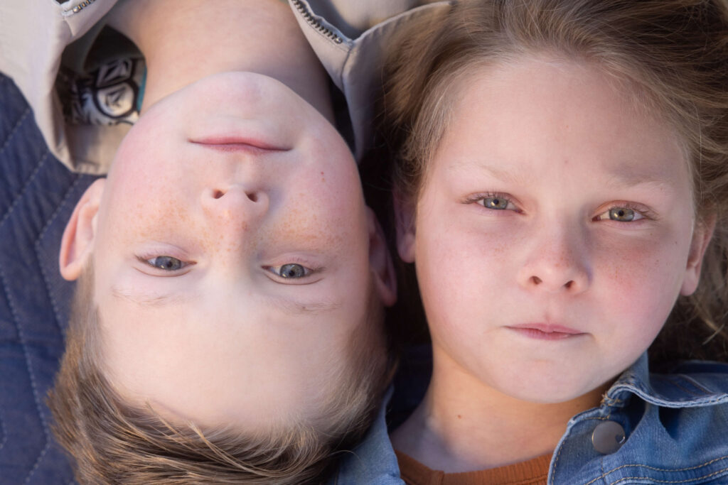 blonde boy and girl laying on blanket with serious facial expressions