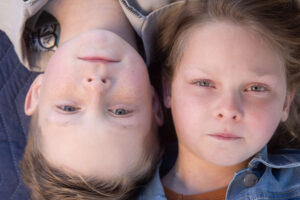 blonde boy and girl laying on blanket with serious facial expressions