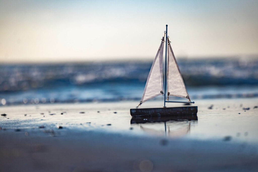 toy sail boat at the beach in the sand