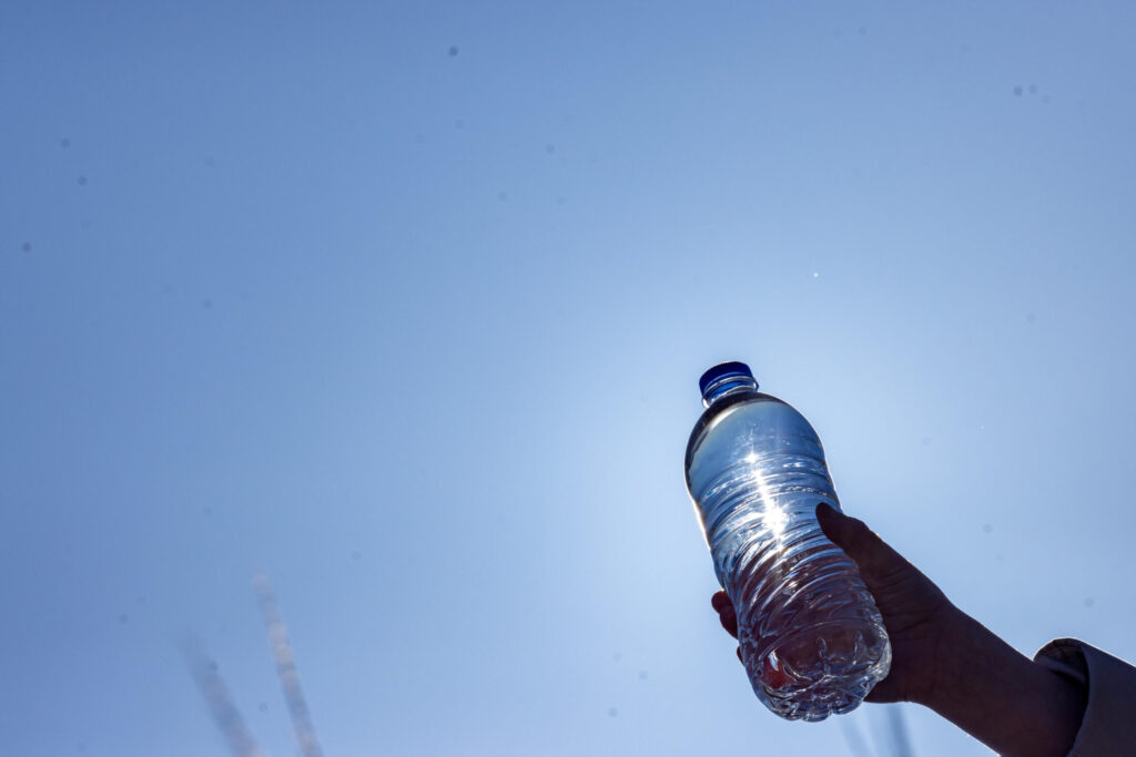 young child holding a water bottle against blue sky background