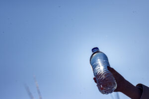 young child holding a water bottle against blue sky background
