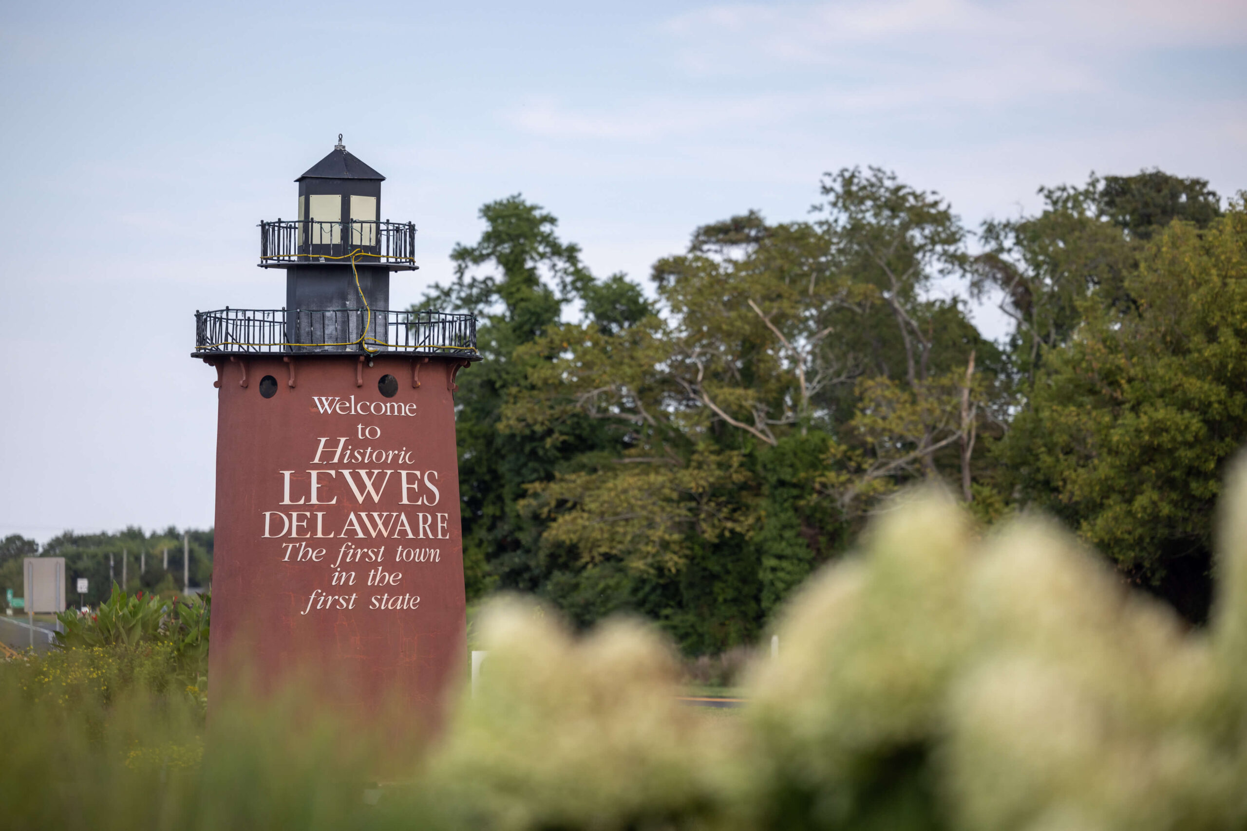 small red lighthouse that reads "welcome to historic lewes delaware: the first town in the first state"