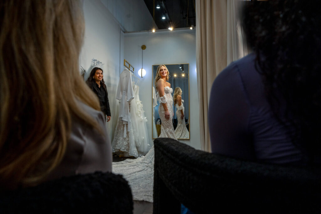 bride laughing in a changing room while wearing a wedding dress