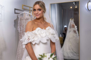 blonde woman smiling lightly in a elegant wedding dress with white flowers