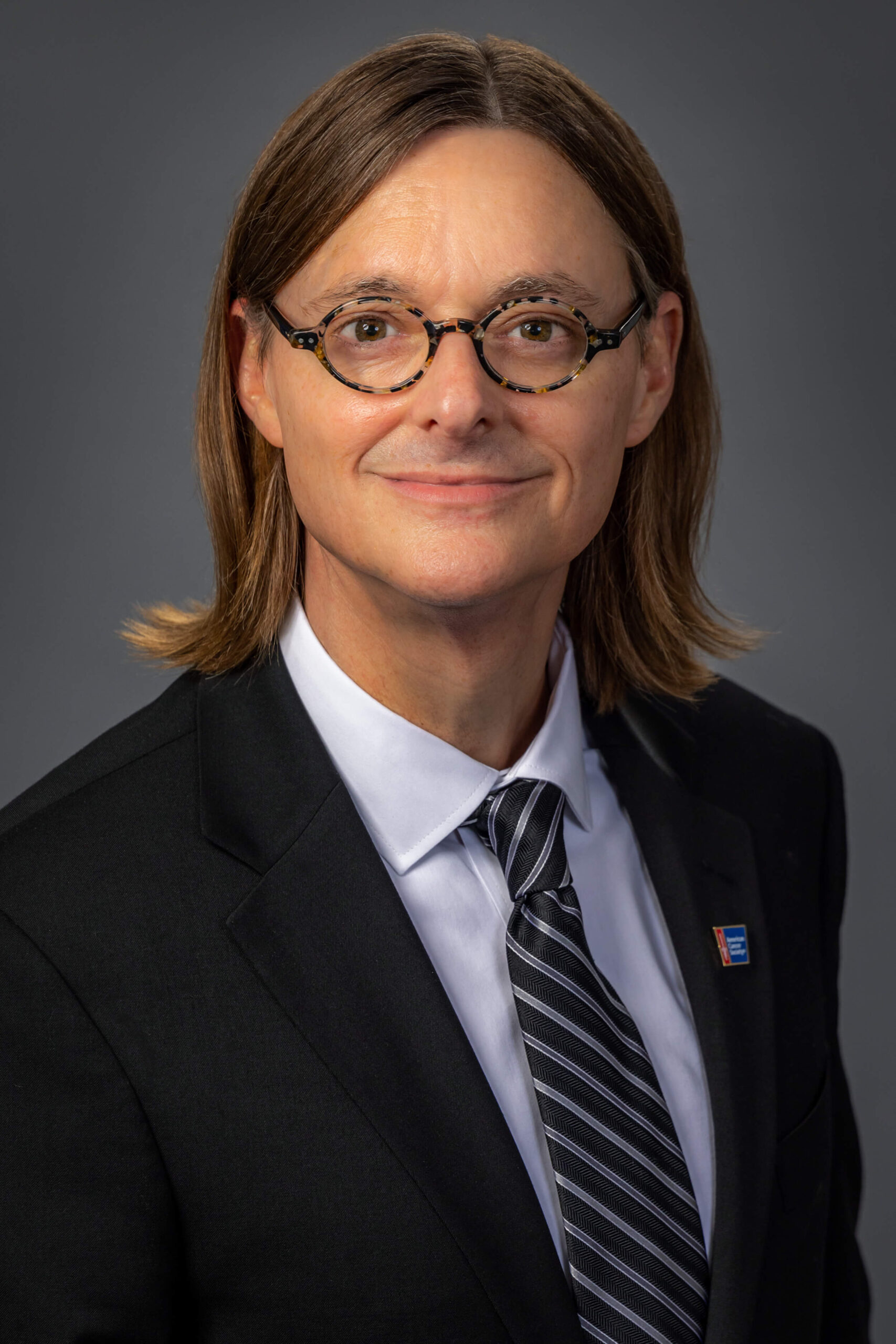 man in tortoise shell glasses and corporate suit and tie