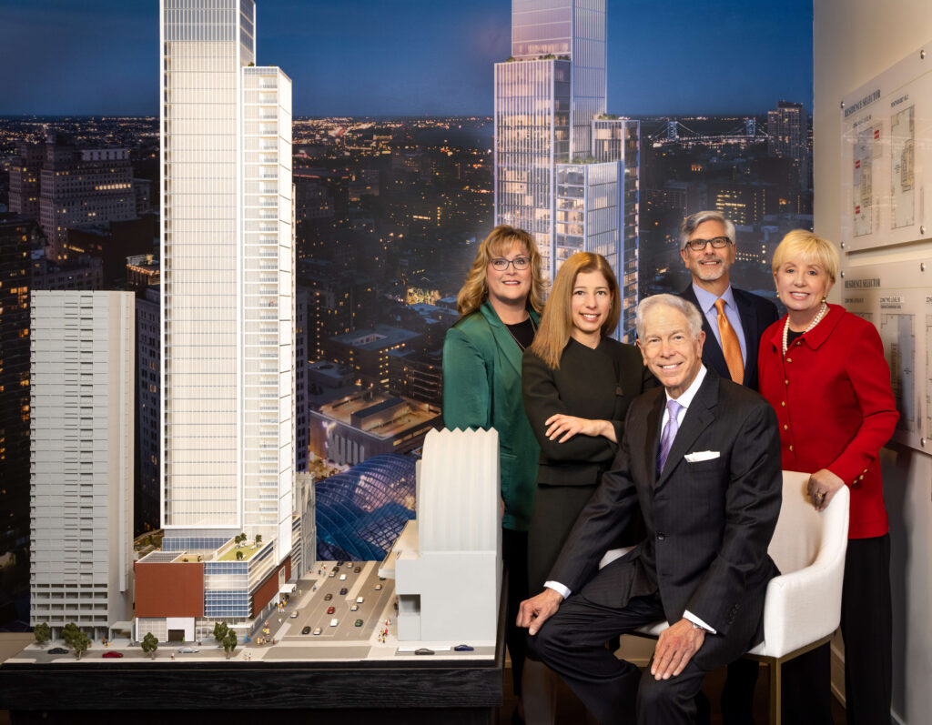 real estate development group posing in room with model building