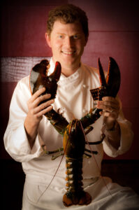 head chef bobby flay holds a lobster and smiles