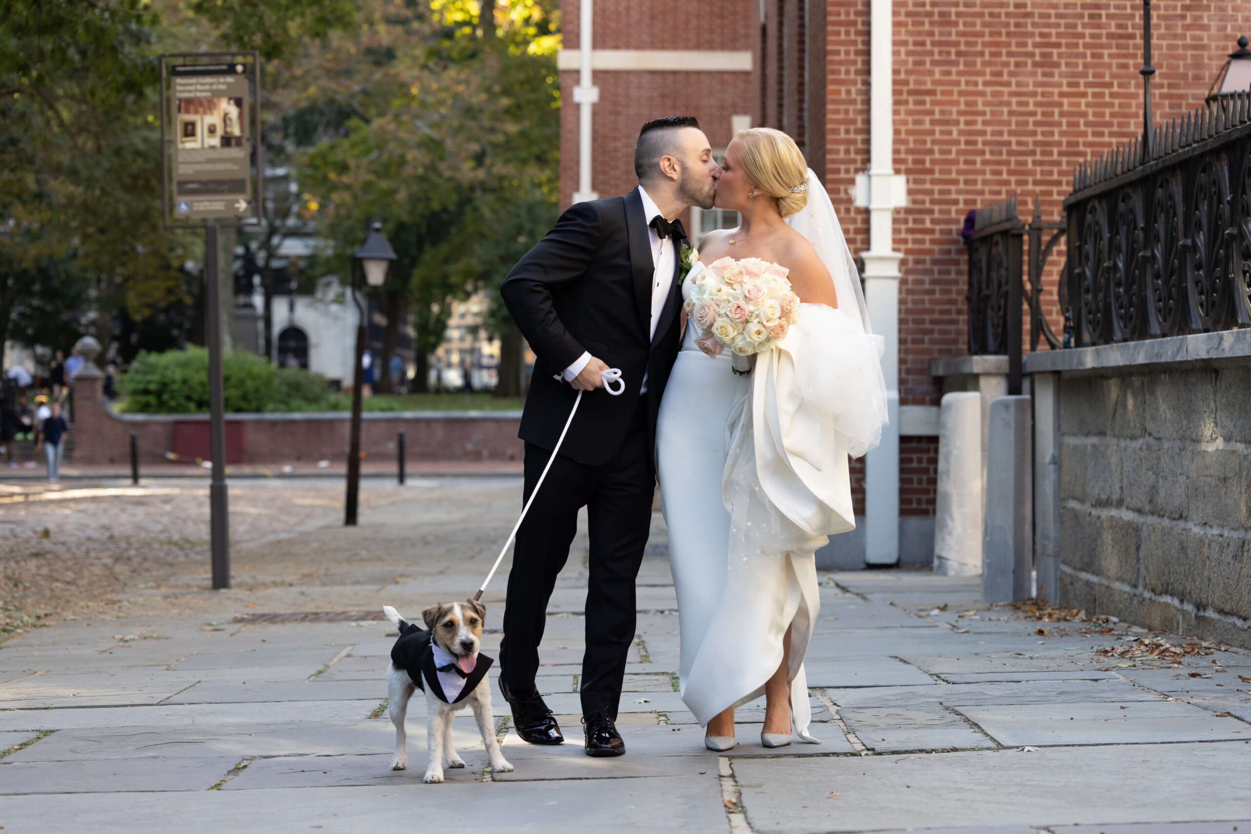 business man leaning against a wood wall in a brown patch suit with denim jeans and brown shoes