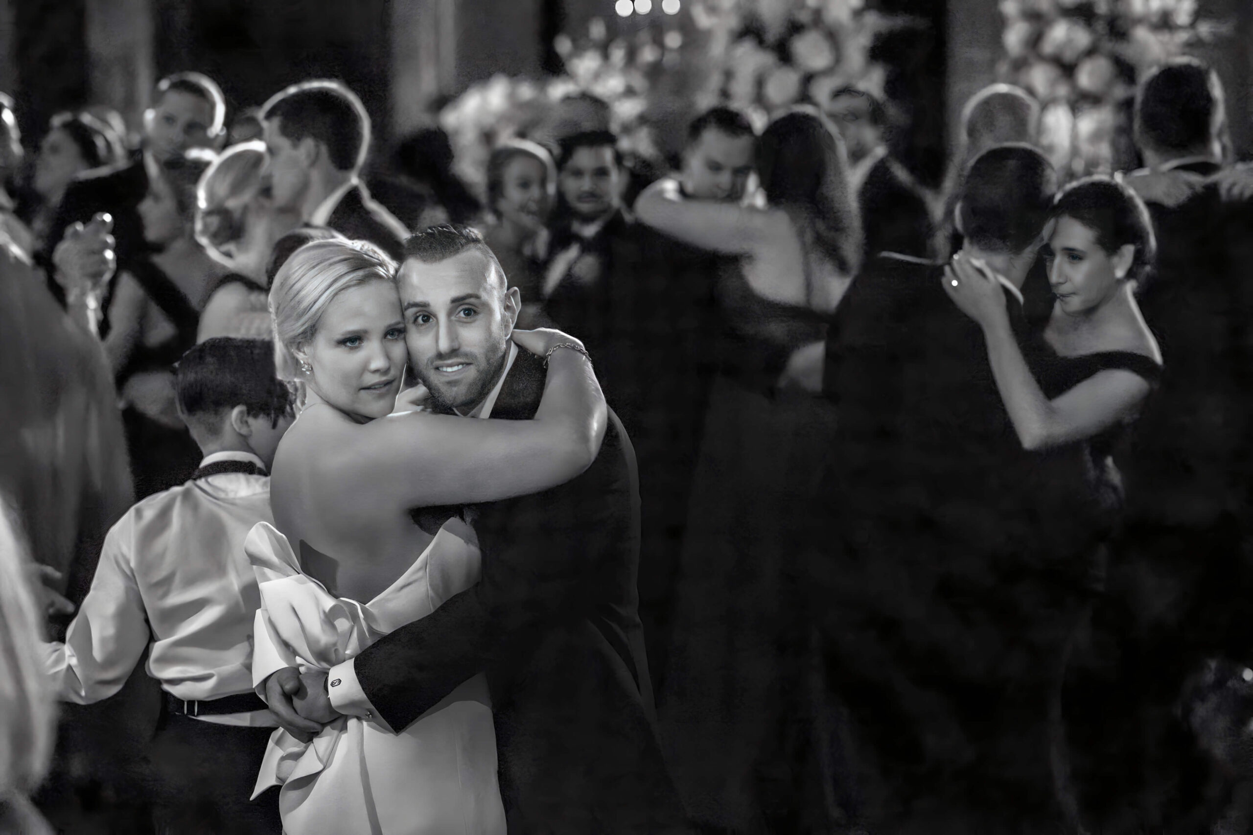 bride and groom posing at art museum with philly skyline behind them on sunny day