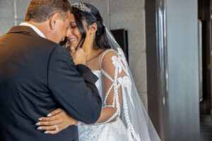 bride in wedding dress crying during a first look with father in a luxury hotel suite