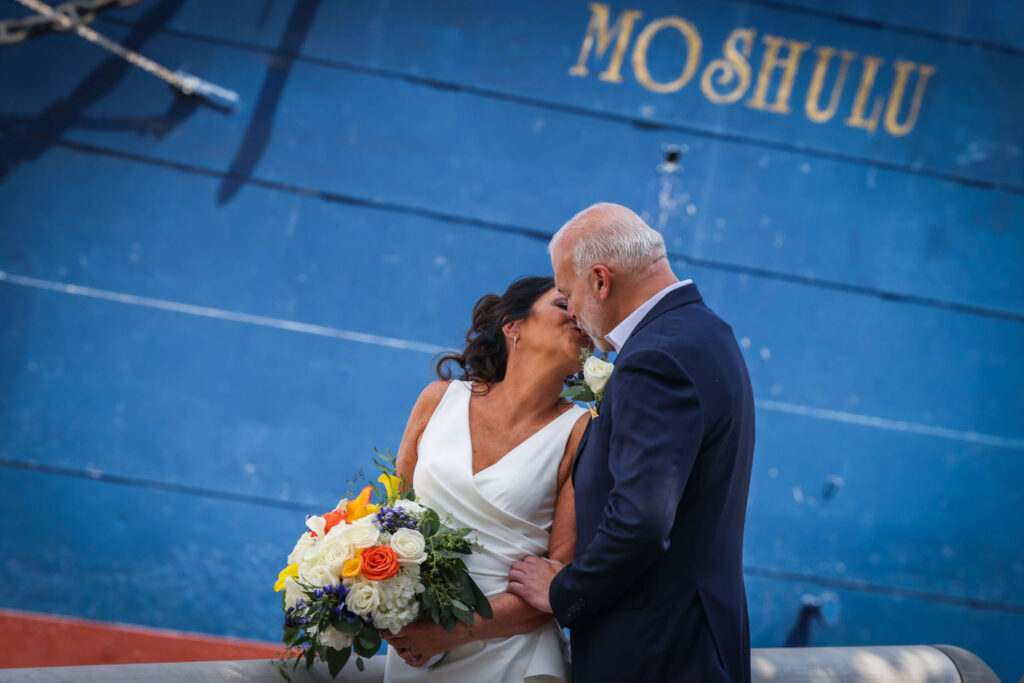 bride and groom share a kiss on their wedding day near the moshulu in philadelphia