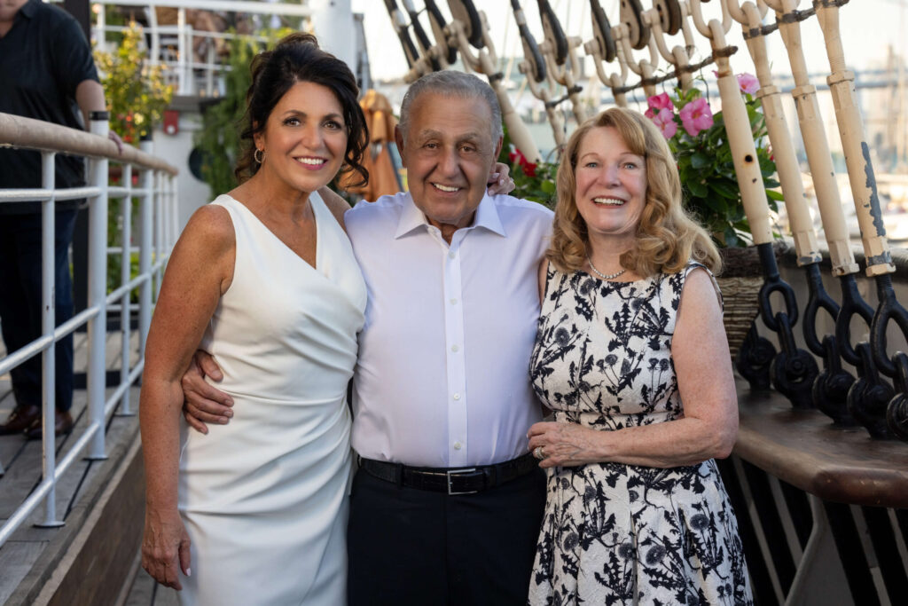 two women and a man in a white shirt pose for a group photo aboard the moshulu in philadelphia
