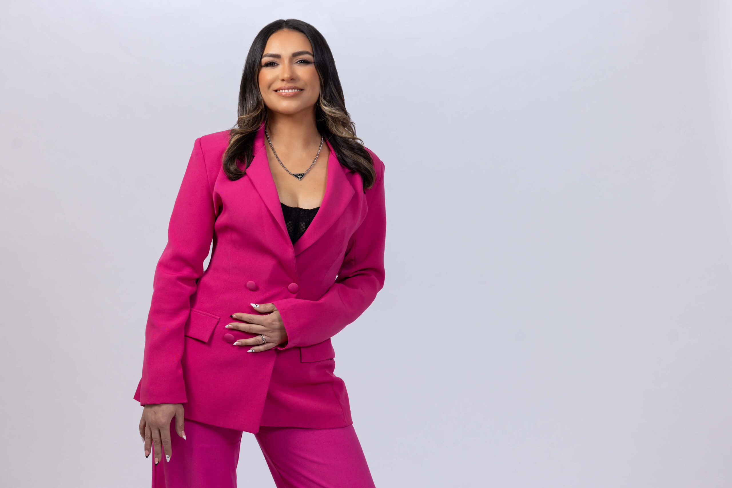 women in hot pink suit posing against a white background