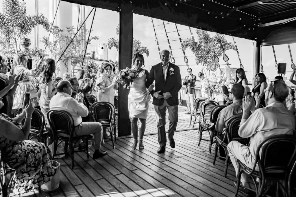 black and white photo of emotional bride and groom walking down ceremony aisle at the moshulu