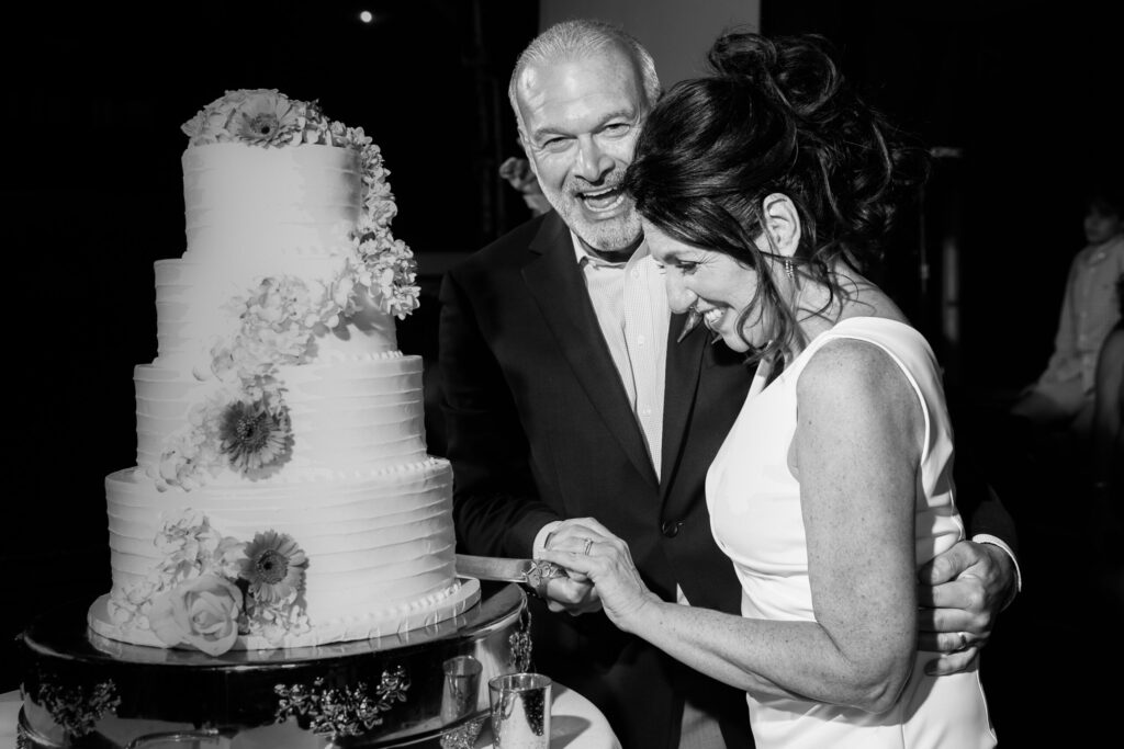 bride and groom smiling as they cut their wedding cake