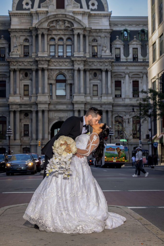 bride and groom leaning and kissing at broad street city hall in philadelphia