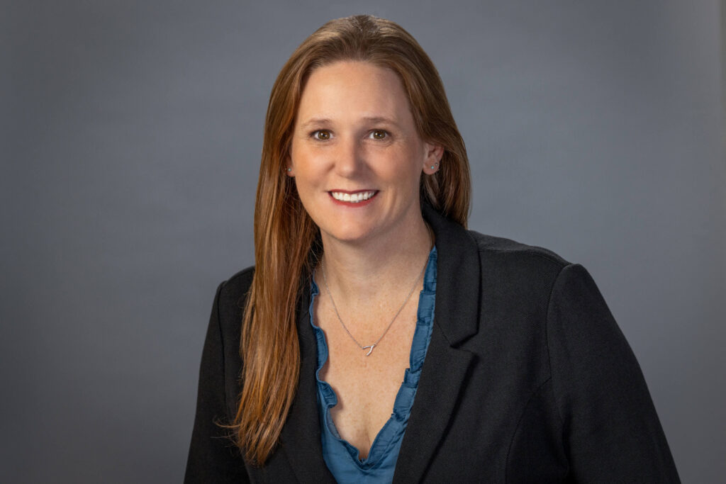 woman in teal blouse and black blazer smiling with confidence for camera