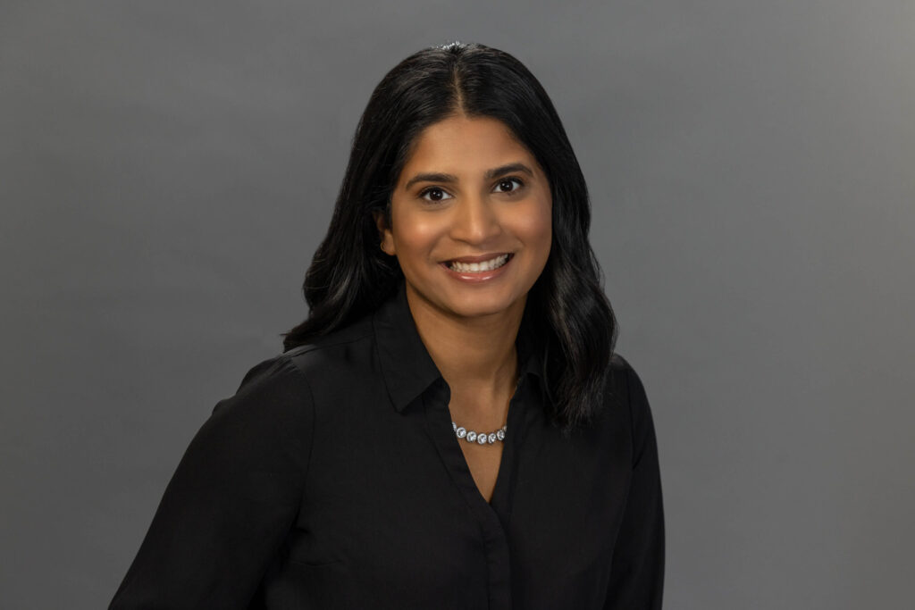 woman in all black shirt posing against a gray background in photo studio
