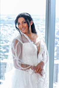 bride in wedding dress by large window with philly city view