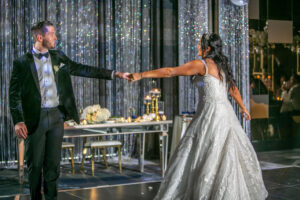 bride and groom holding outstretched hands during wedding reception first dance celebration