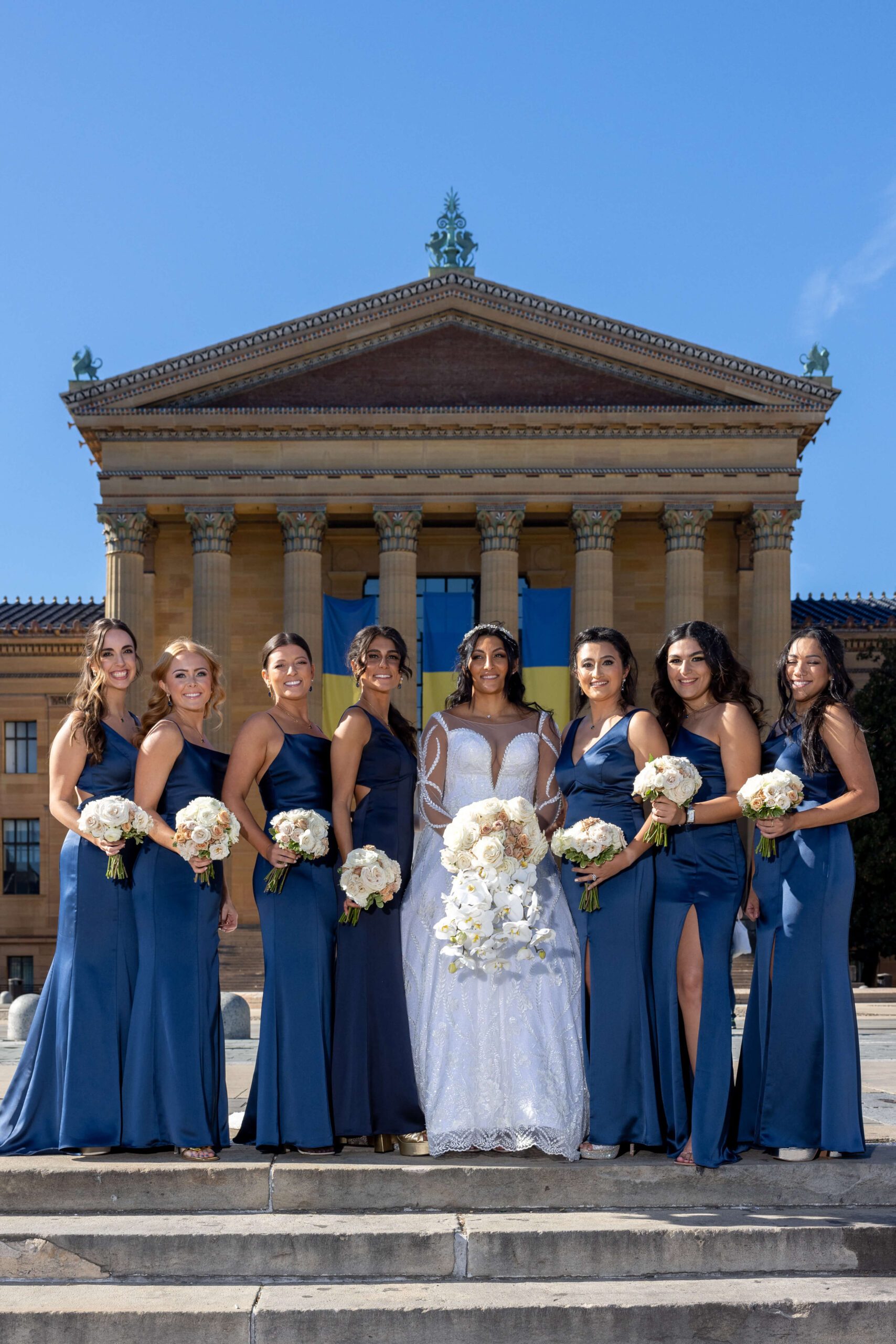 bride and bridesmaids posing at front of the museum of art in philly