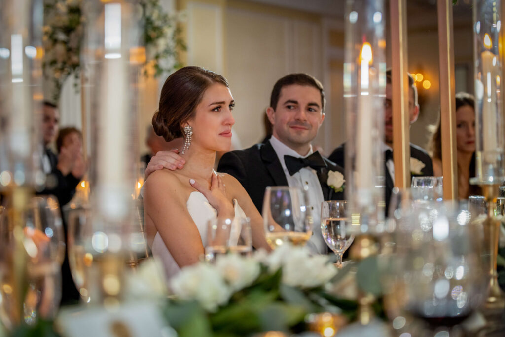 groom comforting crying bride at wedding reception table