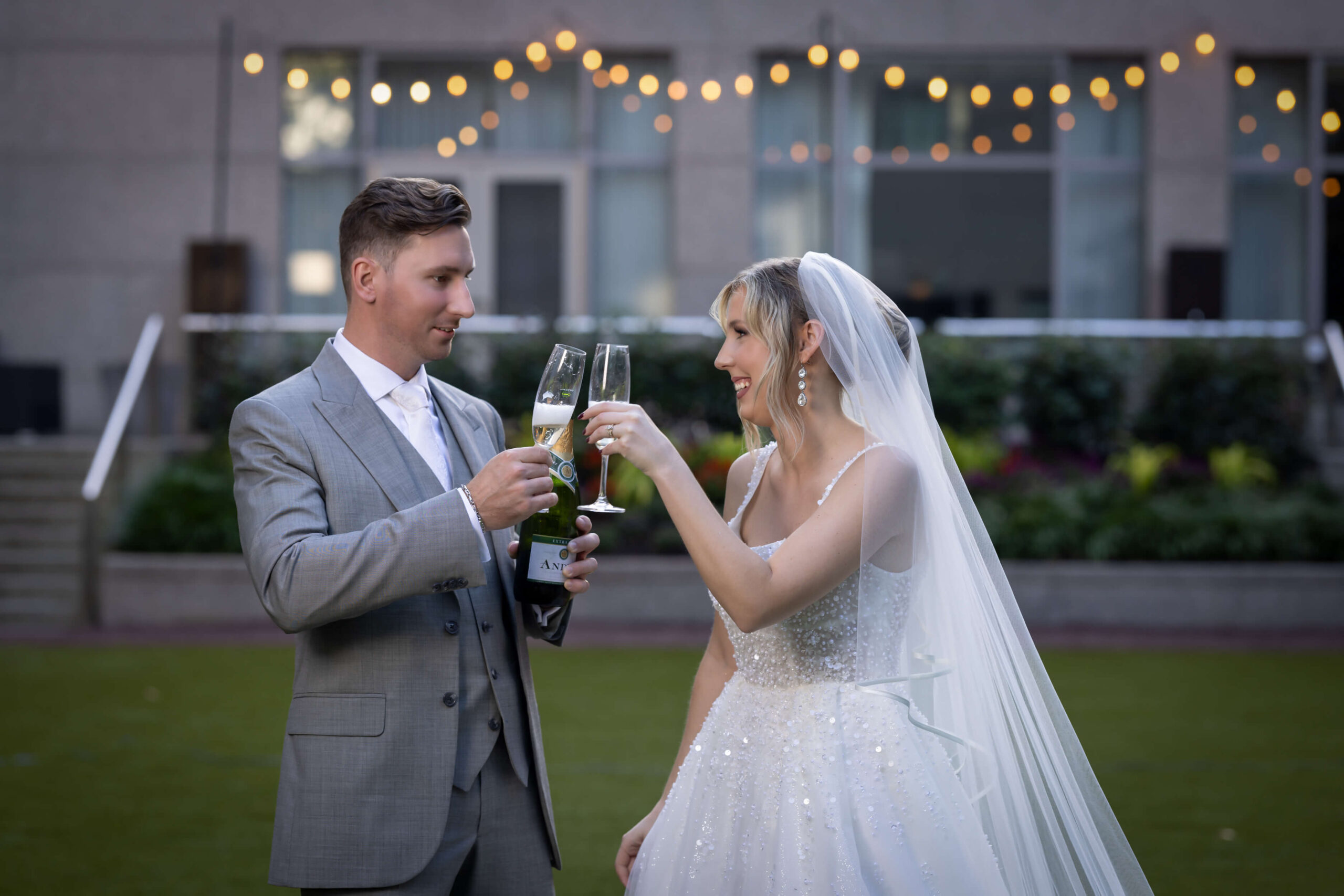 cheerful bride and groom toast with champagne glasses in the courtyard at the logan